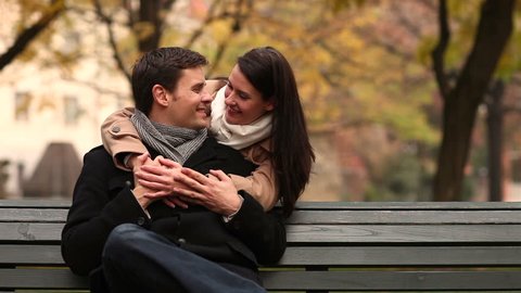 Woman embracing and kissing man in park and both holding thumbs up