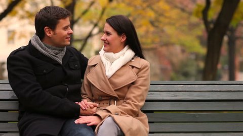 Woman and man talking on a park bench in autumn 