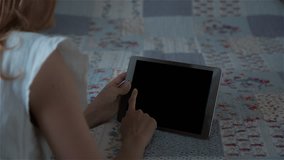 High quality 10bit footage of Beautiful girl using tablet pc with isolated screen lying on bed at home. Made from RAW footage.