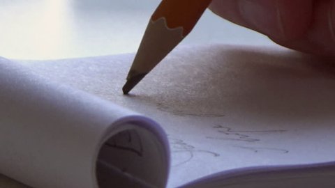 Hand with pencil writing a letter on paper