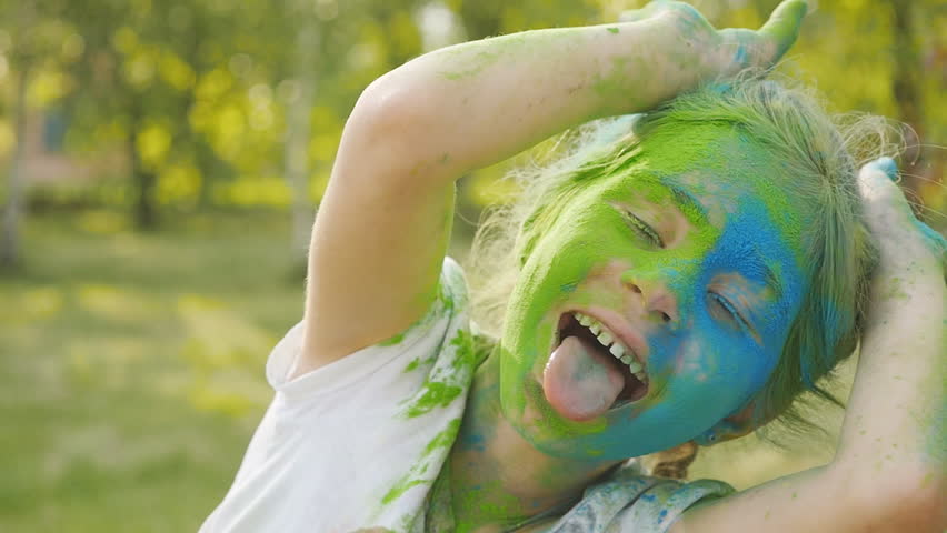 Portrait of a cute girl painted in the colors of Holi festival.
