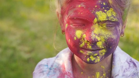 Portrait of a cute girl painted in the colors of Holi festival.