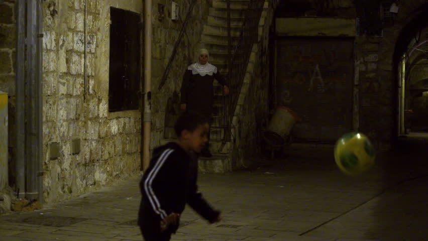 ISRAEL - FEB 2011: Boy kicking a soccer ball in an alley at night in the city of