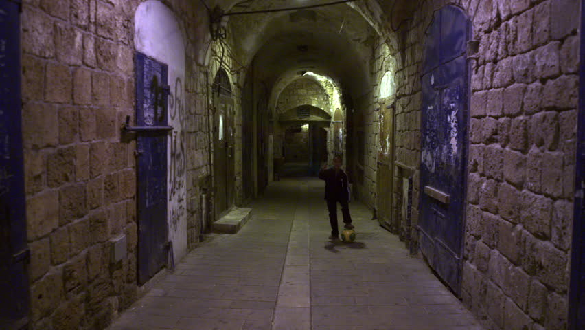 ISRAEL - FEB 2011: Dolly shot of a boy Kicking a soccer ball in an arched alley