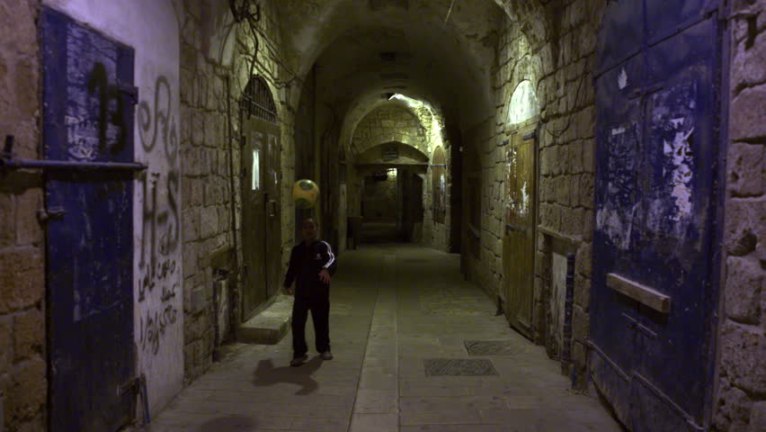 ISRAEL - FEB 2011: Dolly shot of a boy kicking a soccer ball in an arched alley