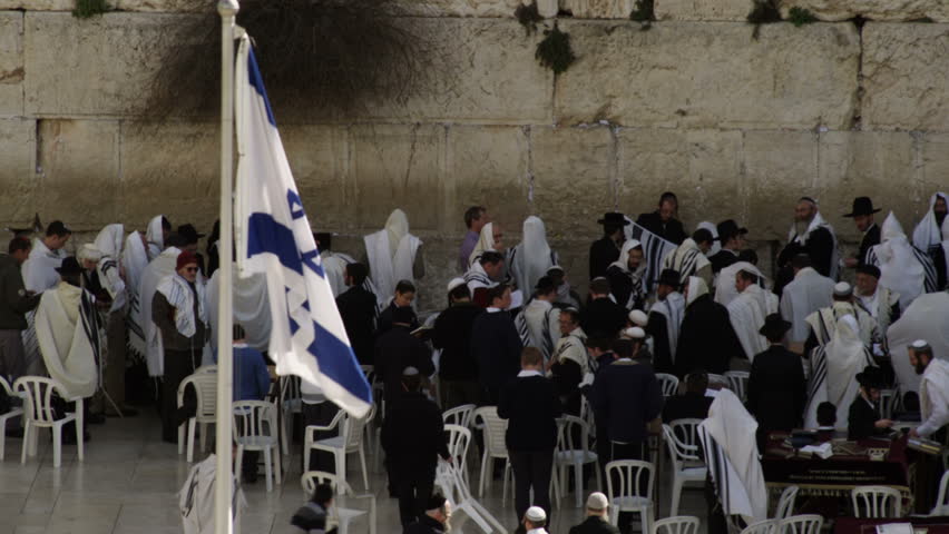 ISRAEL - FEB 2011: Israeli flag in the foreground and male Jews at the Western