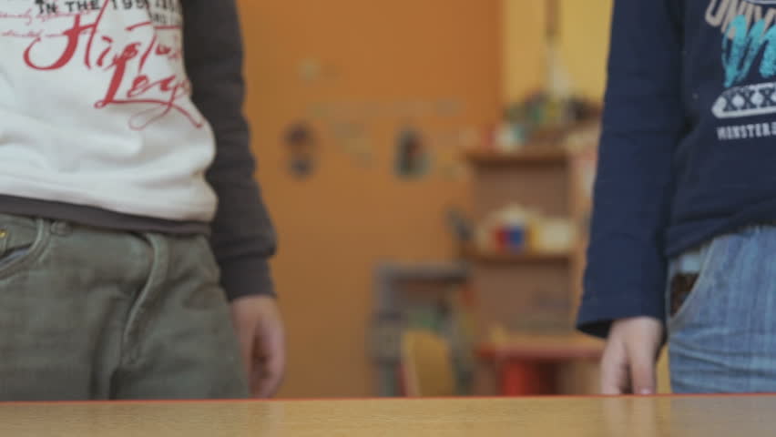 Two boys play toy model cars at the table