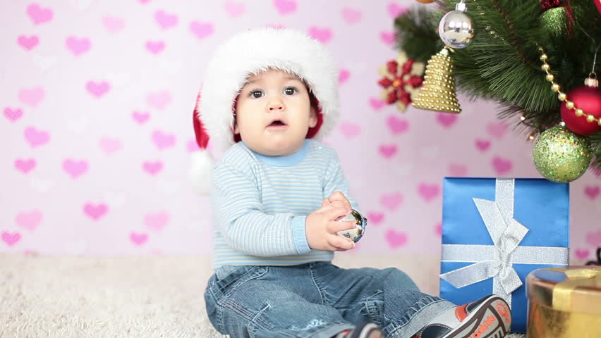Baby boy in Santa Claus hat sitting on the floor