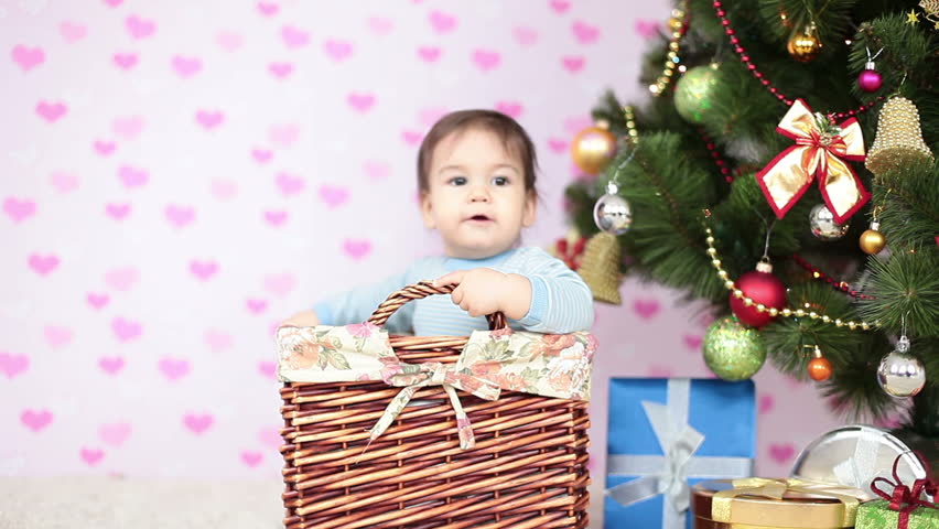 Baby boy sitting in a basket near the Christmas Tree