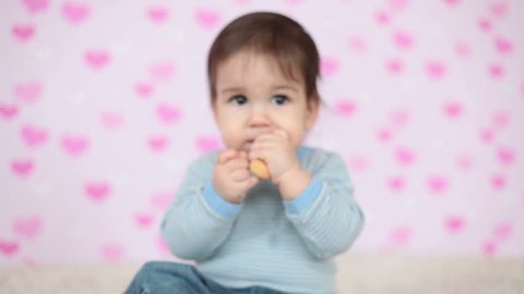 Closeup portrait of a baby boy eating a cookie sitting on the floor