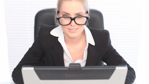 Fun Portrait Woman Wearing Huge Glasses, a businesswoman sits at her laptop wearing huge black framed glasses in a humorous portrait