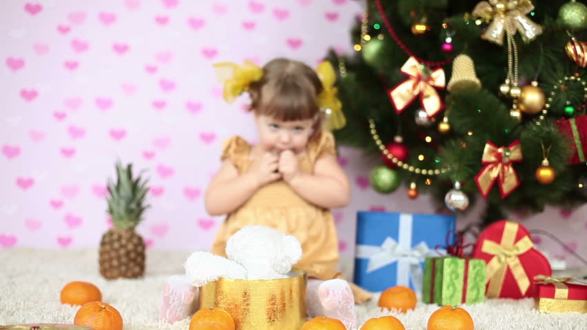 Baby girl eats a chocolate under the Christmas tree
