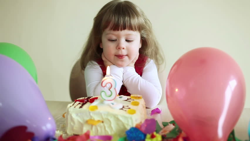 Child with a birthday cake looking at camera