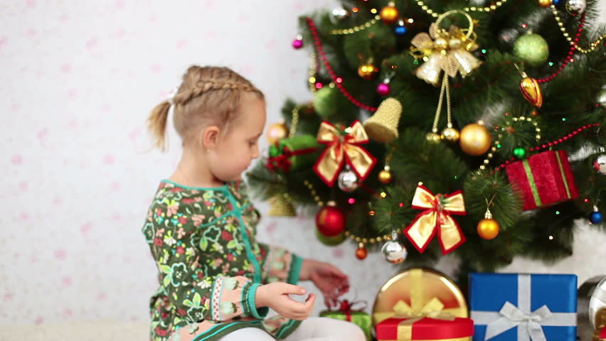 Girl chooses a gift under the Christmas tree