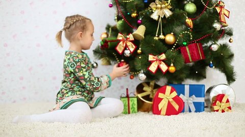 Happy girl sitting near a Christmas tree