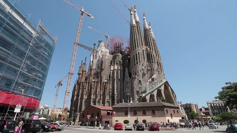 BARCELONA, SPAIN - MAY 21 2011: Cathedral Sagrada Familia famous church and landmark with tourists and locals in city park in Barcelona, Spain on May 21, 2011. Traffic on road.