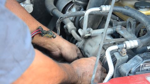 Old man 60 year old thai people professional automotive motor mechanic repair and inspecting the alternator in car at local shop in Nonthaburi, Thailand