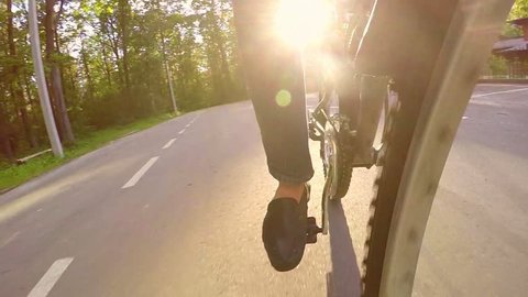 Slow motion man cyclist riding on a paved road near the forest at sunset, backlight, front camera shoots
