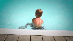 Cute little boy having fun in a swimming pool, first time learning to swim, with pleasure swimming on a body board, spending summer holidays on a beach resort. Full HD Video 1920x1080