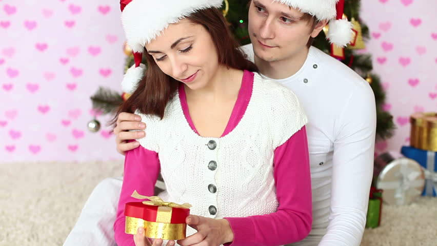 Couple in Santa hats hugging and sitting on the floor