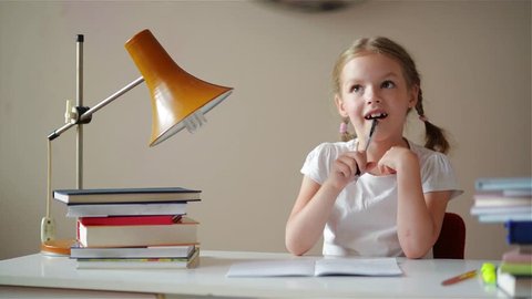 Girl learning lessons, cute girl making her homework, schoolgirl studing at home at the table, children's education, back to school