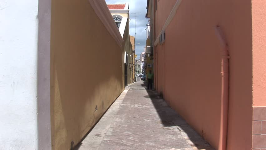 CURACAO - CIRCA MAY, 2009: People walk down narrow alley in between buildings.