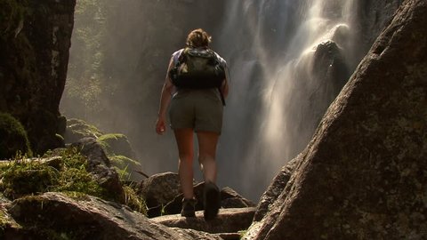 Female hiker admires waterfall from bottom