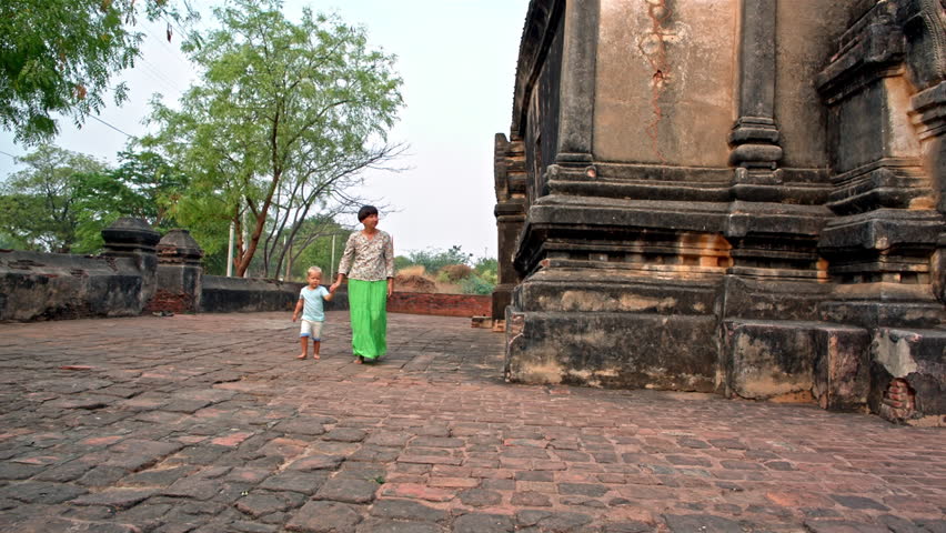 young woman walks with toddler son along the temple walls in the ancient Bagan city in Myanmar (formerly Burma)