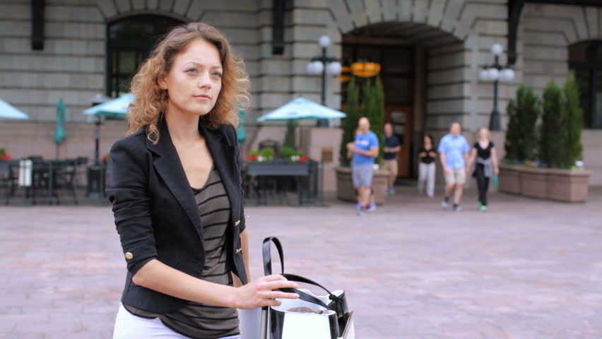 Young woman in front of the train station with suitcase.