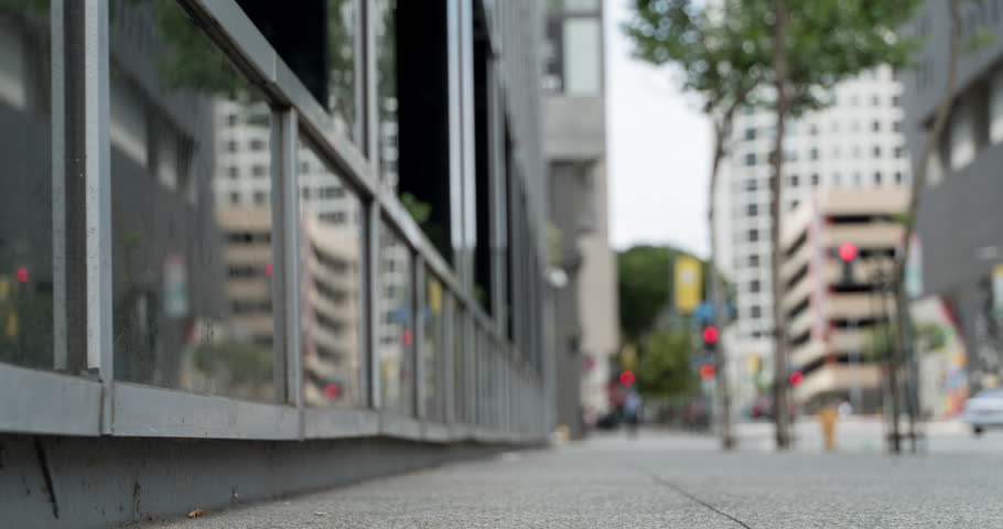 People and traffic walking next to reflective building in Downtown Los Angeles.  Shallow depth of field with focus on foreground.  Time lapse.