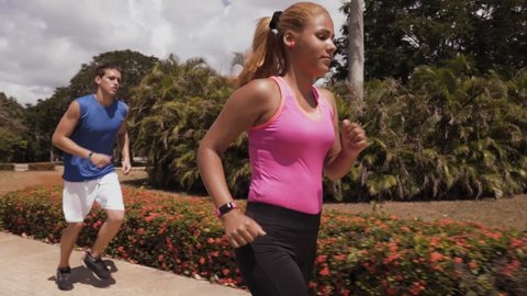 Young people doing sport, girl and friend running, man and woman jogging with fit watch, happy friends and couple. Leisure, recreation, fitness, exercise, training, workout. Slow motion, steadicam