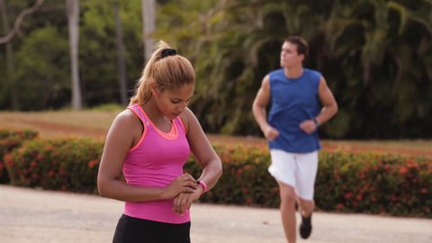 Young people doing sport activities, girl and friend running, using fit watch, man and woman jogging on the street. Leisure, health, recreation, fitness, lifestyle, exercising, training, workout