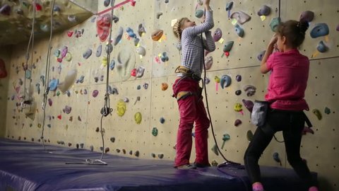 Two girls pulling a safety rope next to the climbing wall