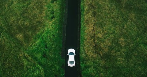Aerial view electric car driving on country road, luxury car driving through mist at dusk with headlights