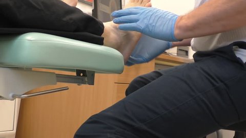 Doctor podiatrist is examining male patient's foot in his office