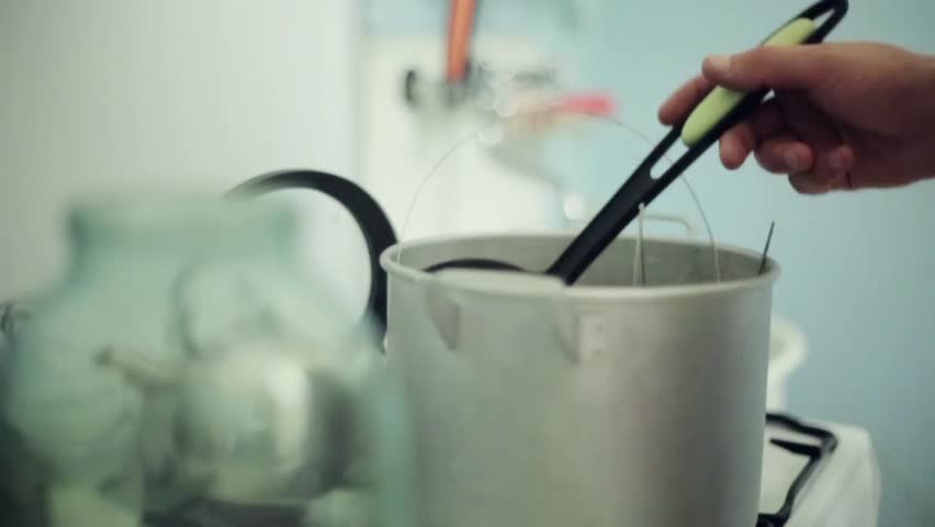 Man hand got out soup ladle from saucepan with inedible objects on gas stove. Art house cooking