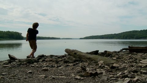 Kid skips rocks across water