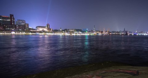 Hamburg, Germany - panorama view over river Elbe from south shore to illuminated skyline with Landungsbruecken, church Michel and Elbphilharmonie at night - Timelapse with motion and zoom 