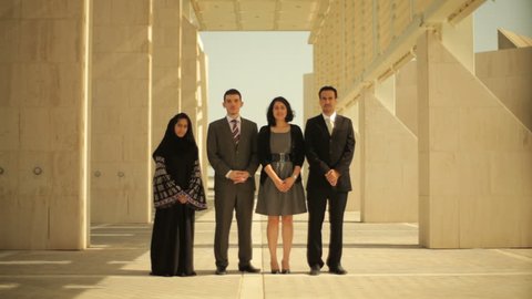 Bahrain portrait. Still on young Bahraini business men and women in the grand marble colonnade of a modern building talking to each other.
