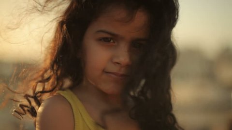 Muharraq, Bahrain - circa 2011 - CU of a little Bahrain girl with long curly hair blowing across her face. She is looking into the camera and smiling. 