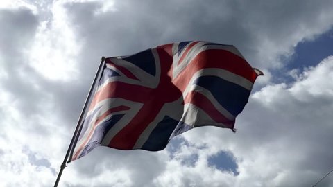 National flag of Great Britain United Kingdom  England waving in the wind in a sunny day with a cloudy blue sky in background 