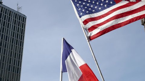 Sun and ray of light behind the waving national flag of United state of America and France with a cloudy blue sky in background Stockvideó
