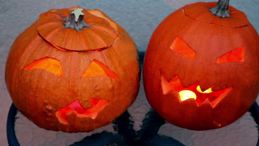 Two pumpkins of halloween lie on glass little table  