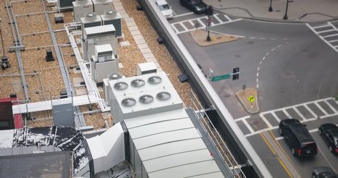 A high angle shot of rooftop air conditioner units on a commercial building.  	