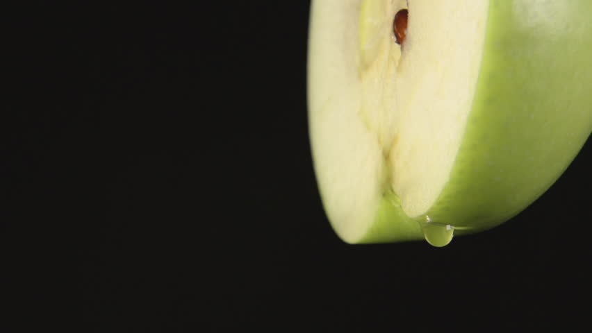 SLOW MOTION: A drops of a juice drip from a green apple