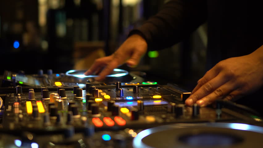 DJ plays music mixing and scratching on turntable music equipment. Professional music equipment with lights and controls being played by male disc jockey. In a dark club, turntables are lit up. | Shutterstock HD Video #17388178