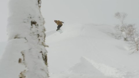 Male Snowboarder Does a Jump, Crashes and Flips in the Powder Snow. Potentially an Injury or Concussion Causing Accident.