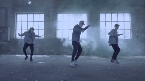 Video of active young group dancing choreography in an abandoned building with smoky background.