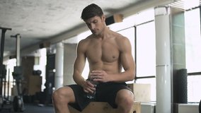 Healthy fitness man drinking water while resting in the gym