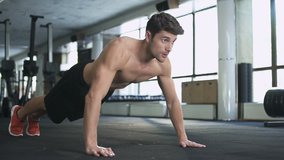 Handsome fitness man doing push ups in gym